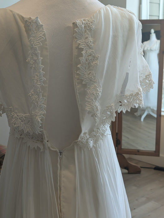 Back view of a Pine Eco + Refillery Boutique vintage-inspired white wedding gown with intricate floral lace trim.