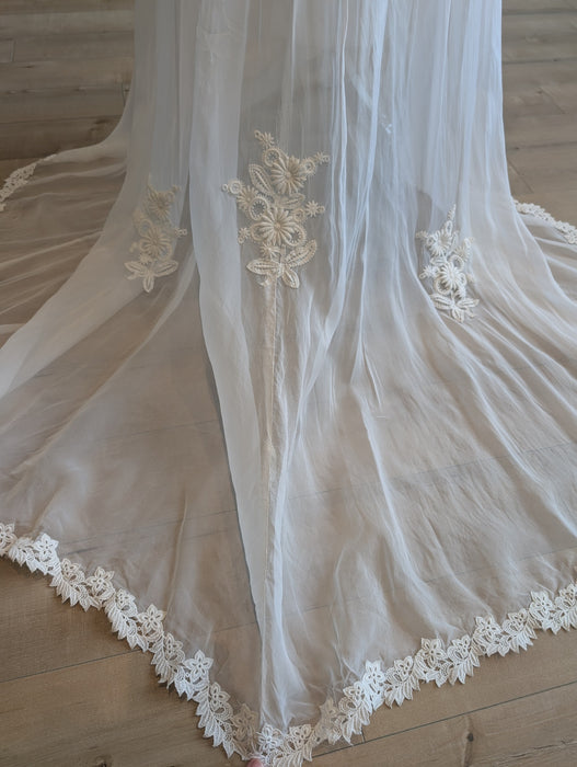 Pine Eco + Refillery Boutique white wedding gown featuring intricate floral lace appliqué and a sweeping lace-trimmed train