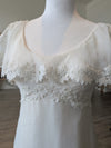 Pine Eco + Refillery Boutique vintage-inspired white wedding gown with delicate floral lace appliqué and flutter sleeves.