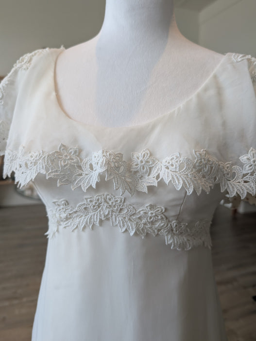 Pine Eco + Refillery Boutique vintage-inspired white wedding gown with delicate floral lace appliqué and flutter sleeves.